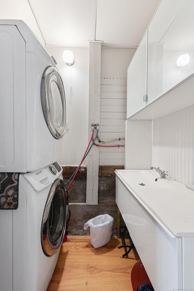 washroom with sink, stacked washing maching and dryer, and light wood-type flooring