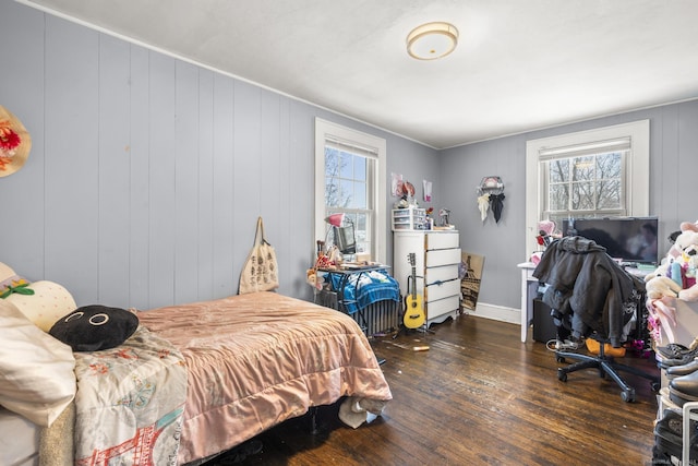 bedroom with multiple windows, wooden walls, and dark hardwood / wood-style flooring