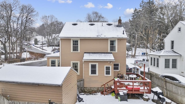 snow covered back of property featuring a deck