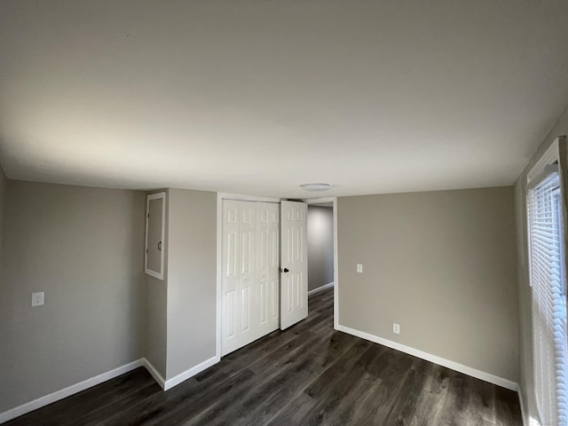 unfurnished bedroom with electric panel, a closet, and dark hardwood / wood-style floors