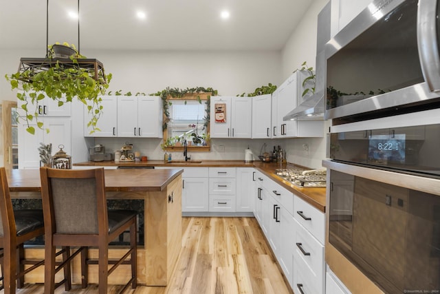 kitchen featuring wooden counters, light hardwood / wood-style floors, white cabinetry, and sink