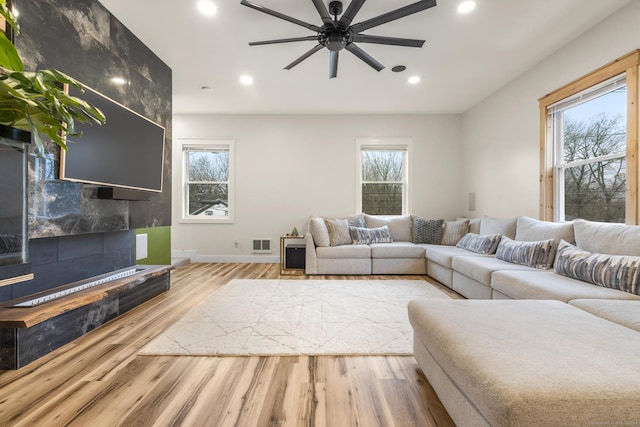 living room with plenty of natural light, ceiling fan, and light hardwood / wood-style flooring