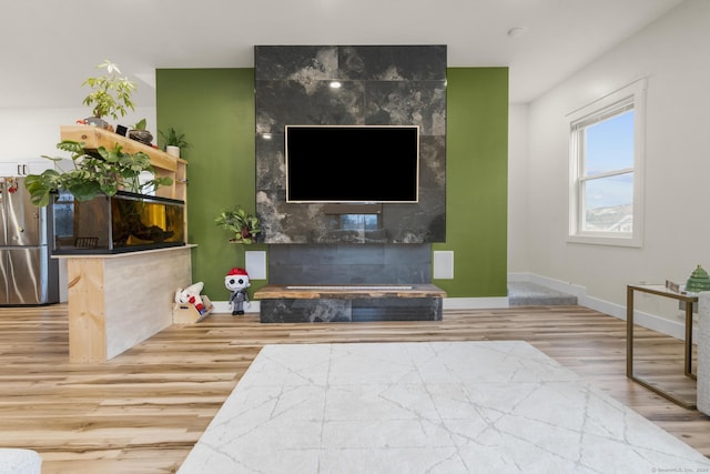 living room with wood-type flooring and a tile fireplace