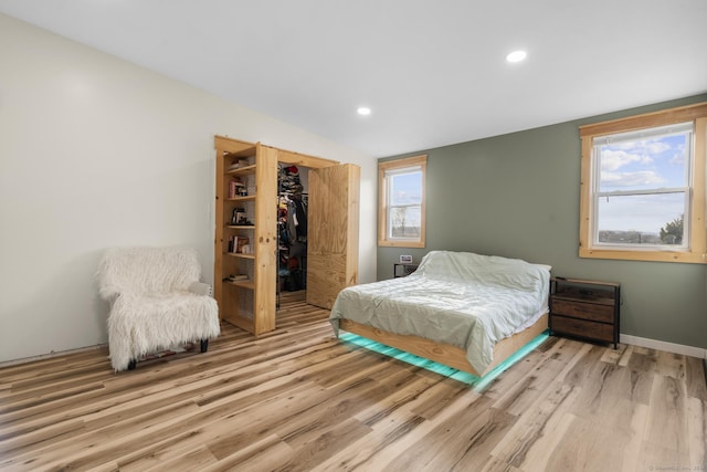 bedroom with a walk in closet, light hardwood / wood-style floors, and a closet