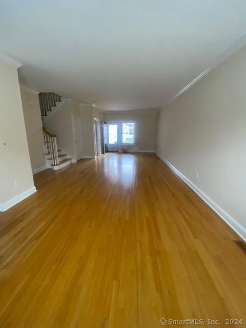 unfurnished living room featuring hardwood / wood-style flooring and crown molding