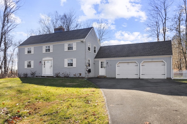 colonial-style house featuring a front yard and a garage