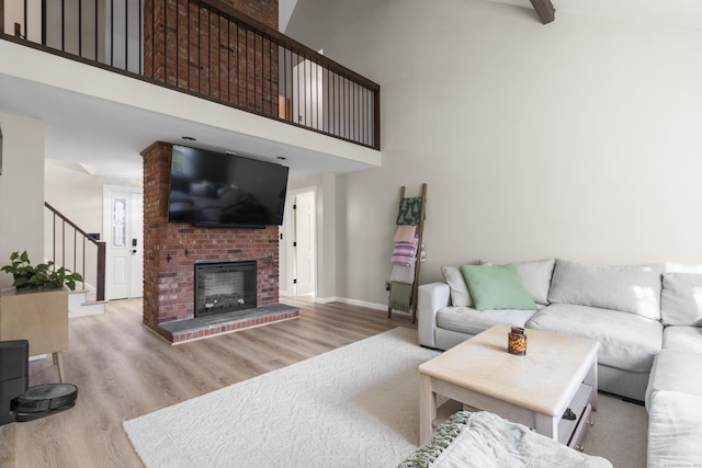 living room with a fireplace, a high ceiling, and light hardwood / wood-style floors