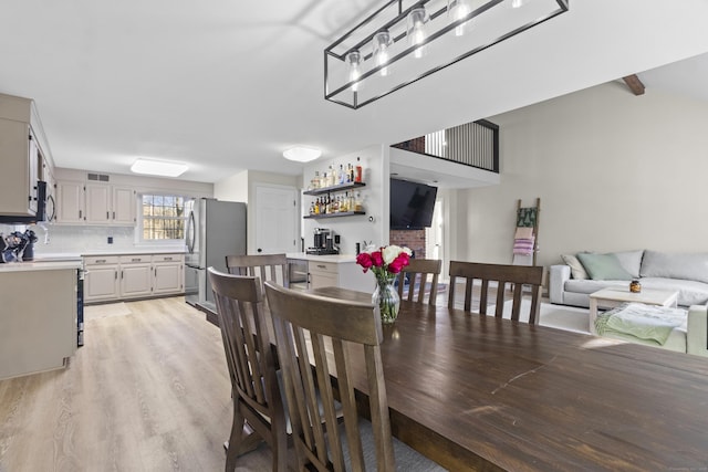 dining area featuring light wood-type flooring and indoor bar