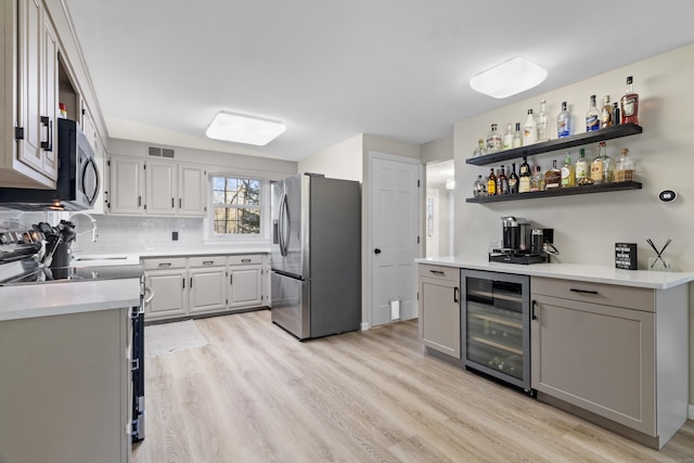 kitchen featuring wine cooler, light hardwood / wood-style flooring, gray cabinets, and stainless steel appliances