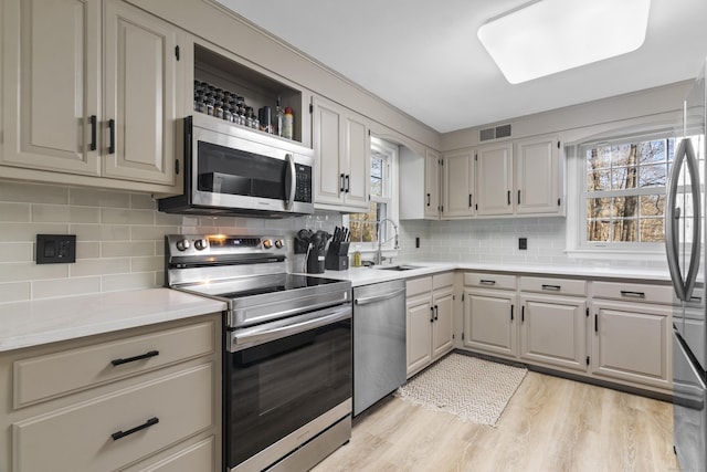 kitchen with stainless steel appliances, tasteful backsplash, a healthy amount of sunlight, and sink