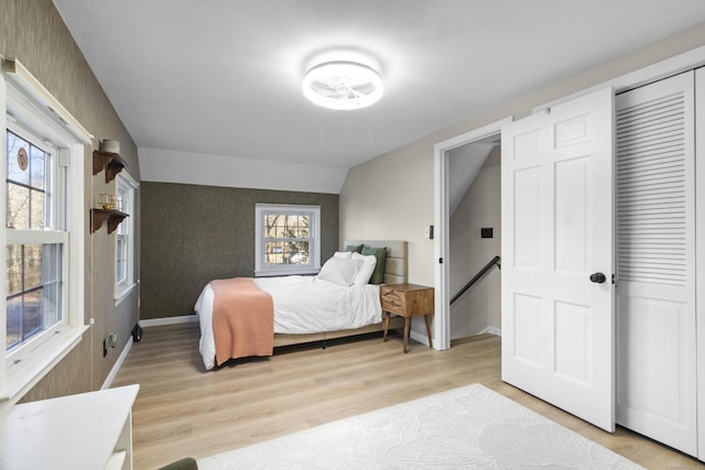 bedroom featuring multiple windows, vaulted ceiling, and light wood-type flooring