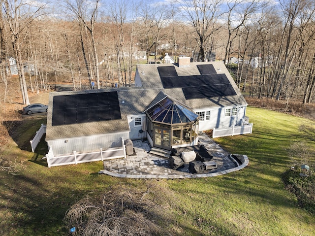 back of house with a lawn, a sunroom, and solar panels