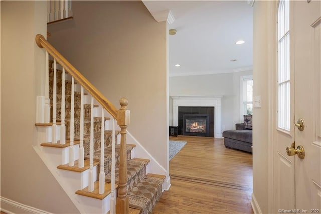 stairway featuring hardwood / wood-style floors, a fireplace, and crown molding