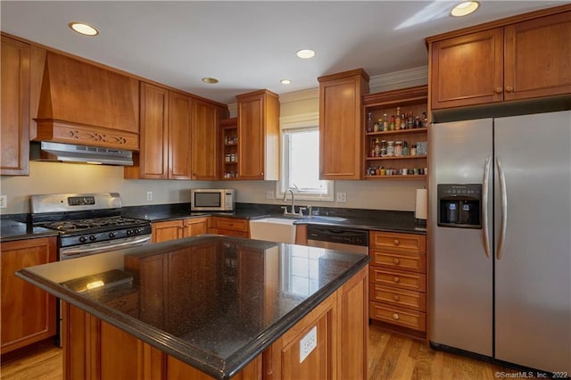 kitchen with light wood-type flooring, stainless steel appliances, sink, a kitchen island, and range hood