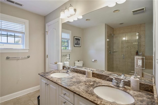 bathroom with tile patterned flooring, vanity, a shower with shower door, and a wealth of natural light