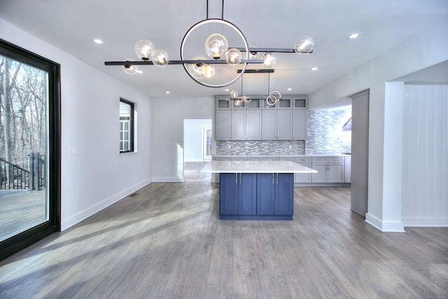 kitchen with gray cabinets, pendant lighting, tasteful backsplash, a large island, and light hardwood / wood-style floors