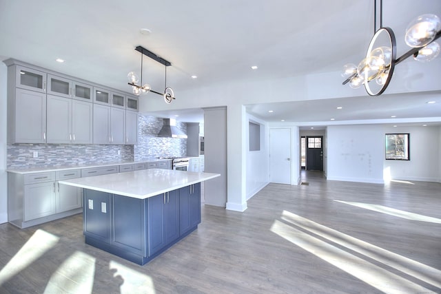 kitchen with a kitchen island, pendant lighting, decorative backsplash, wall chimney range hood, and an inviting chandelier