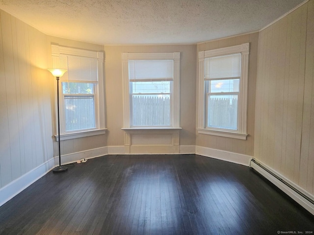 unfurnished room featuring dark hardwood / wood-style flooring, a textured ceiling, and a baseboard heating unit