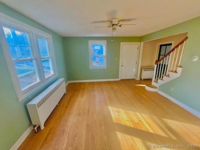 unfurnished room with radiator, ceiling fan, and light hardwood / wood-style floors