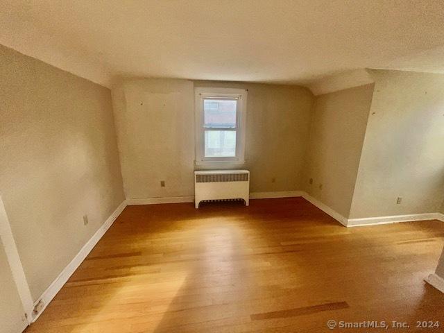 spare room featuring hardwood / wood-style floors and radiator heating unit