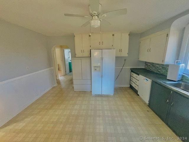 kitchen with white appliances, backsplash, sink, ceiling fan, and white cabinetry