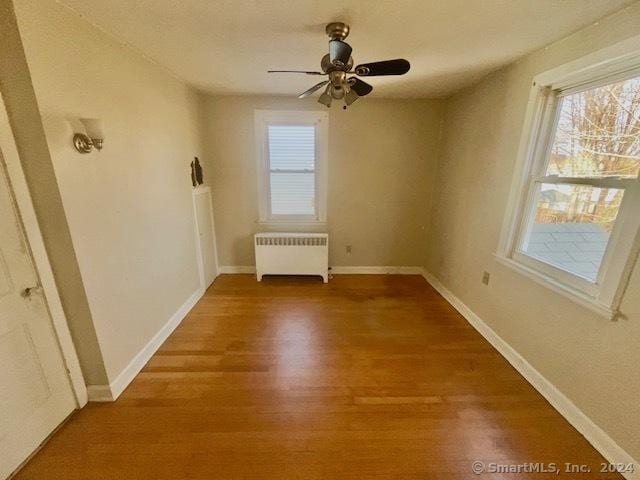 empty room with radiator, ceiling fan, and hardwood / wood-style flooring