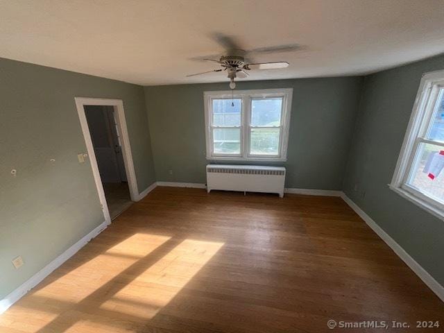 unfurnished room with ceiling fan, radiator heating unit, and hardwood / wood-style floors