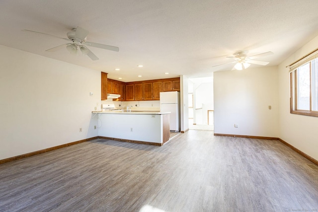 unfurnished living room with ceiling fan, light hardwood / wood-style flooring, and a textured ceiling