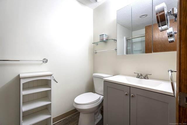 bathroom with toilet, vanity, a textured ceiling, and hardwood / wood-style flooring