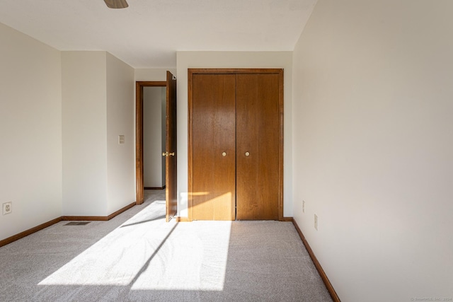 unfurnished bedroom featuring light colored carpet, a closet, and ceiling fan