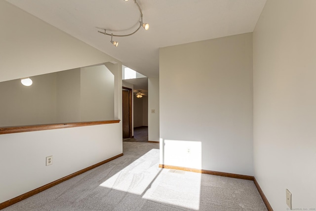 empty room with ceiling fan, light colored carpet, and rail lighting