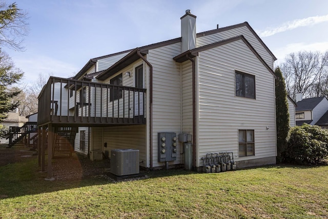 view of side of property featuring a yard, a wooden deck, and central AC