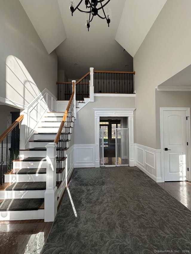 stairway featuring carpet floors, high vaulted ceiling, ornamental molding, and a notable chandelier