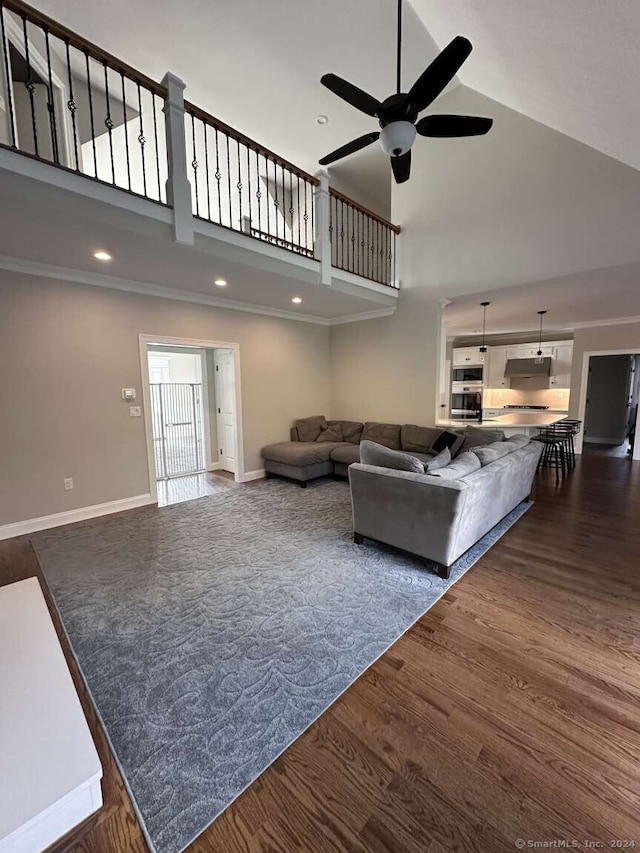 living room with a towering ceiling, dark hardwood / wood-style floors, and ceiling fan