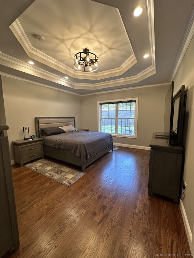 bedroom with a tray ceiling, crown molding, dark hardwood / wood-style floors, and an inviting chandelier