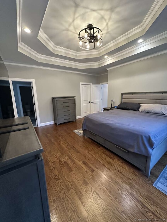 bedroom with dark hardwood / wood-style flooring, a raised ceiling, and ornamental molding