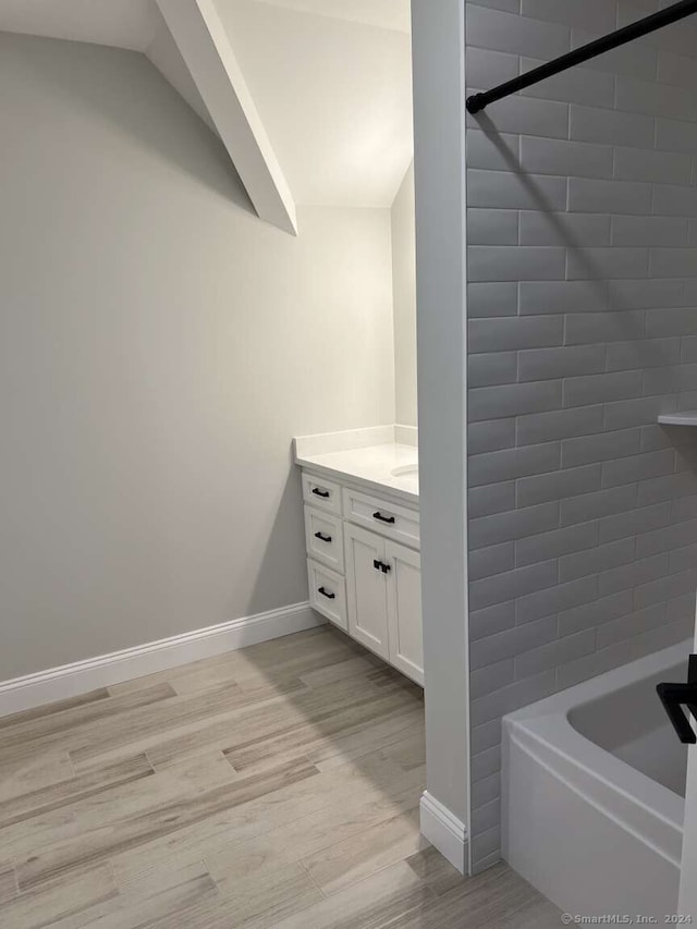 bathroom with hardwood / wood-style floors, vanity, and tiled shower / bath combo