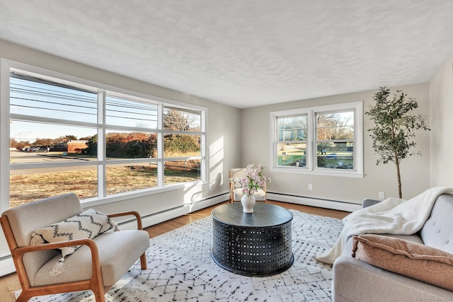 living room featuring baseboard heating, light hardwood / wood-style floors, and a textured ceiling