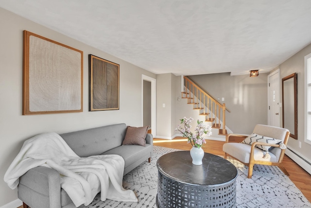 living room featuring wood-type flooring and a baseboard heating unit