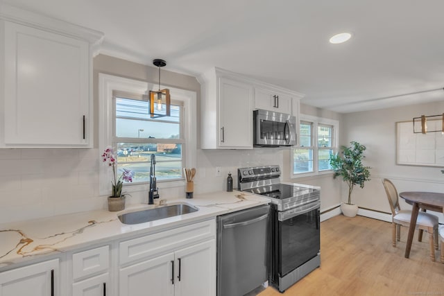 kitchen with stainless steel appliances, baseboard heating, sink, decorative light fixtures, and white cabinets