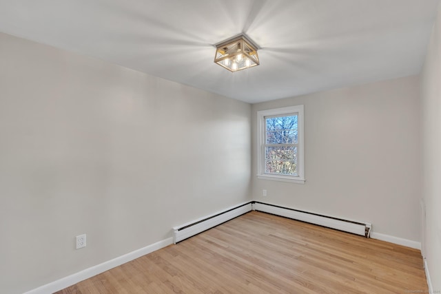 empty room featuring a baseboard heating unit and light wood-type flooring