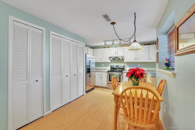 kitchen with decorative light fixtures, light wood-type flooring, white cabinetry, and stainless steel appliances