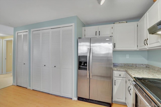 kitchen with stainless steel fridge, light stone counters, extractor fan, light hardwood / wood-style floors, and white cabinetry