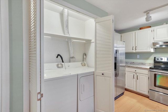 laundry room with light wood-type flooring, rail lighting, and washing machine and clothes dryer