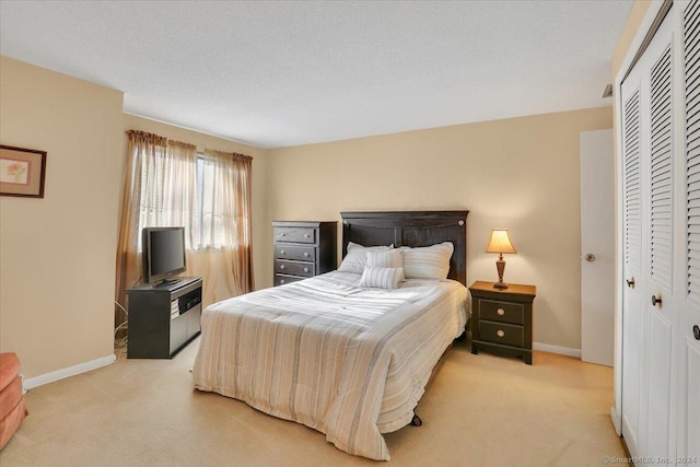 bedroom with light colored carpet, a textured ceiling, and a closet