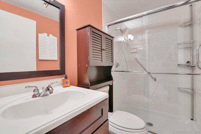 bathroom featuring vanity, toilet, and a shower with shower door