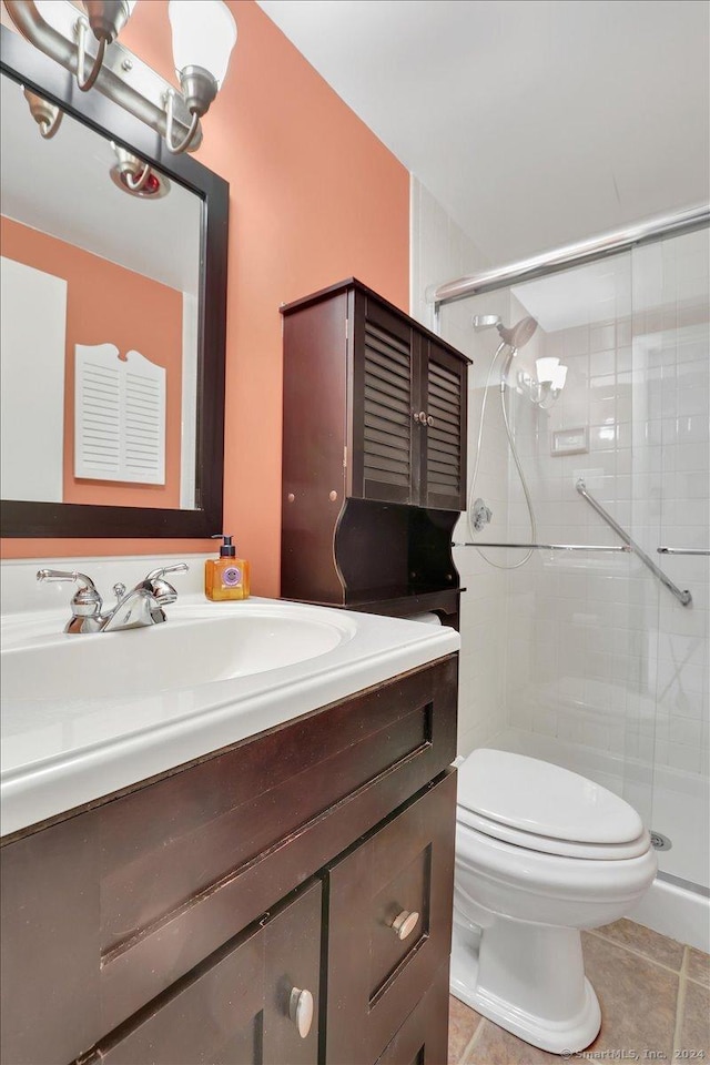 bathroom featuring tile patterned floors, vanity, toilet, and a shower with door