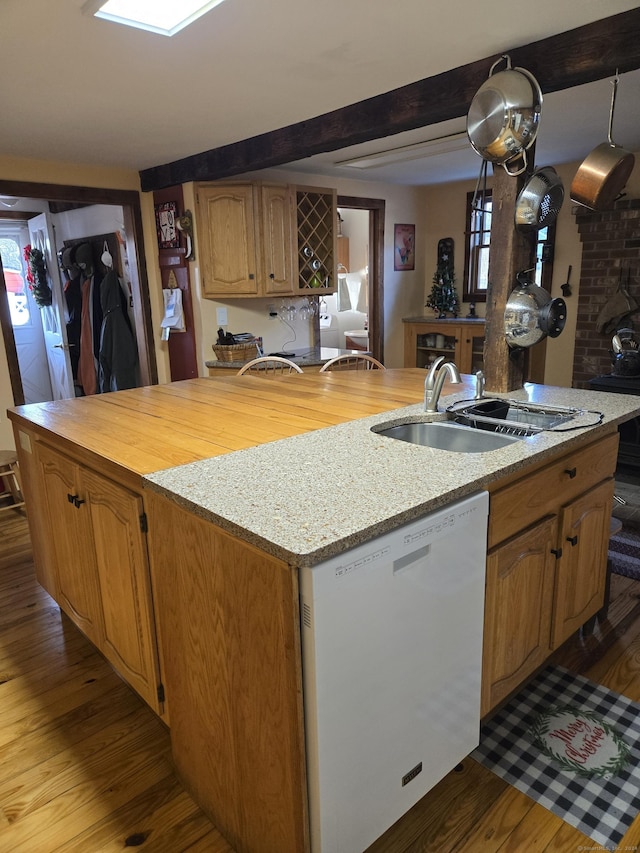 kitchen with beamed ceiling, dishwasher, a kitchen island with sink, and light hardwood / wood-style flooring