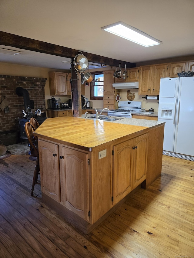 kitchen with white appliances, a center island with sink, sink, light wood-type flooring, and butcher block counters