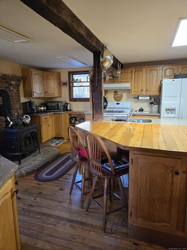 kitchen featuring dark hardwood / wood-style flooring, white appliances, sink, a wood stove, and butcher block counters